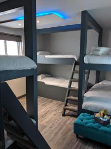 a dorm room with three bunk beds and a blue light at Vibe Holiday Apartments in Blackpool