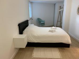 um quarto com uma cama branca e uma cadeira em Jaurès - Centre-Ville - T3 au calme em Brest