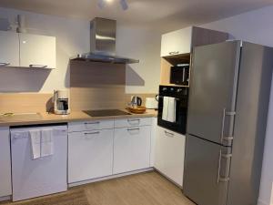uma cozinha com armários brancos e um frigorífico de aço inoxidável em Jaurès - Centre-Ville - T3 au calme em Brest