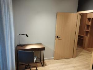 a desk with a lamp and a chair next to a door at Fantastyczny apartament Lotnisko in Poznań