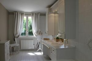 a white bathroom with two sinks and a window at Maison Hermitage in Aincourt