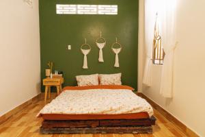 1 dormitorio con cama y pared verde en Phòng Mơ - Nhà Mơ Homestay Bến Tre, en Ben Tre