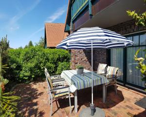 a table and chairs with an umbrella on a patio at Urlaubslust Ferienhaus 14 in Trassenheide