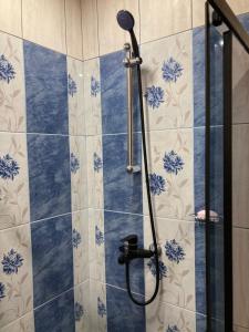 a shower in a bathroom with blue and white tiles at Уютен апартамент Мечта in Vratsa