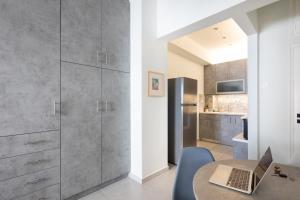 a kitchen with gray cabinets and a table with a laptop at Newly Renovated Cozy Studio Downtown Athens in Athens