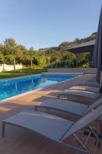 - une rangée de chaises longues à côté de la piscine dans l'établissement Casa do Carvalho - Ponte de Lima, à Ponte de Lima