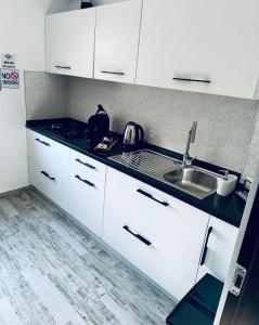 a kitchen with white cabinets and a sink at Natymar in Adjud