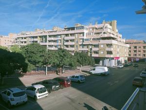 a large building with cars parked in a parking lot at Experience Valencia Bnb - Mare Nostrum Apartment Beach Puerto Sagunto in Puerto de Sagunto