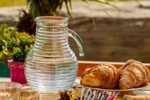 a glass jug and a plate of bread and croissants at B&B Fermata 106 da Carolina in Siculiana Marina