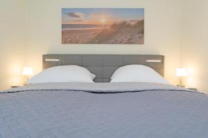 ein Bett mit zwei Kissen und ein Bild von einem Strand in der Unterkunft Residenz Kurparkhöhe Appartement Meerzeit in Scharbeutz