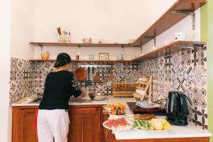 una mujer parada en una cocina preparando comida en Entire First Floor - Nguyên Tầng Trệt- Nhà Mơ Homestay Bến Tre en Ben Tre