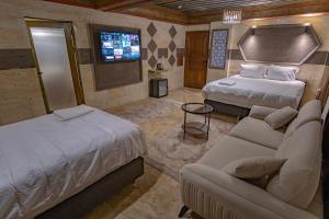 a bedroom with two beds and a couch and a tv at Uçhisar Premium in Nevsehir