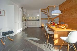 uma cozinha com uma mesa de madeira e cadeiras brancas em Chalet am Breitenberg em Pfronten