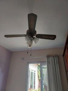 um ventilador de tecto num quarto com janela em Quarto Oceânico - Praia de Piratininga em Niterói