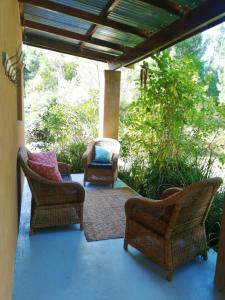 un patio con sillas de mimbre en un porche en Bushman's Pillow, en Sanddrif