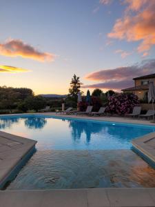 a large swimming pool with a sunset in the background at Hôtel La Bastide d'Iris in Vagnas