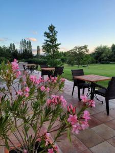 un patio con mesas, sillas y flores rosas en Hôtel La Bastide d'Iris en Vagnas