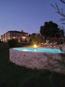 a swimming pool with a stone wall and a house at Hôtel La Bastide d'Iris in Vagnas