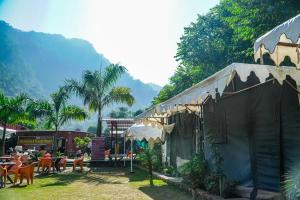 The FnF Resort & Camping - Rishikehs في ريشيكيش: مجموعة طاولات وكراسي أمام المبنى