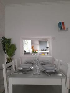 a white table with plates and a wine glass on it at Cosy Apartment with Balcony and Breakfast in Bishop Auckland