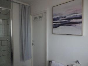 Cosy Apartment with Balcony and Breakfast في بيشوب أوكلاند: حمام به لوحة على الحائط بجانب الدش