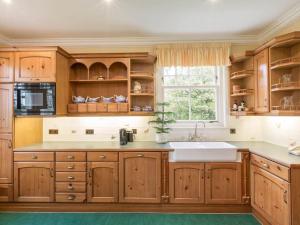 a kitchen with wooden cabinets and a sink and a window at Country Lodge within Castle Ruins and own Loch 20 mins to St Andrews in Ceres