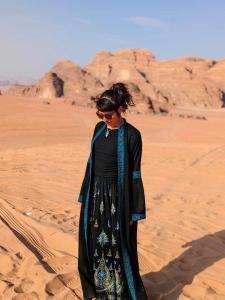 a woman is standing in the desert at Shahrazad desert, Wadi Rum in Wadi Rum