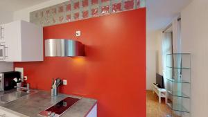 a kitchen with an orange wall and a sink at Unique Serviced Living @ Airport Line in Basel