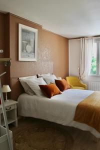 a bedroom with a large white bed with orange pillows at Maison Hermitage in Aincourt