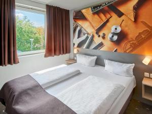 Schlafzimmer mit einem Bett und einem Fenster in der Unterkunft B&B Hotel Offenbach-Süd in Offenbach