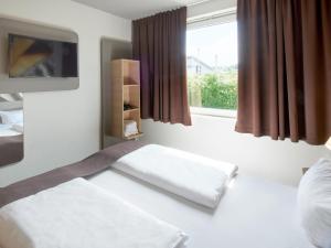 a room with a bed and a window with avertisement at B&B Hotel Offenbach-Süd in Offenbach