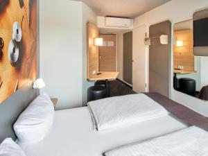 a hotel room with a bed and a desk at B&B Hotel Offenbach-Süd in Offenbach