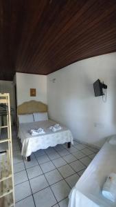a bedroom with two beds and a tv on the wall at Pousada Tropicália Tranquilidade a Beira Mar in Santa Cruz Cabrália