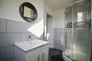 a bathroom with a sink and a shower and a mirror at Roundhay Flat Duplex - Sleeps 2 in Roundhay