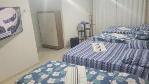 a room with two beds with blue and white sheets at Suite Pajuçara in Maceió