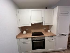 a kitchen with white cabinets and a stove top oven at Ferienwohnung Agena in Schliersee +5 photos
