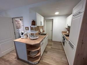 a kitchen with white cabinets and a wooden counter top at Ferienwohnung Agena in Schliersee