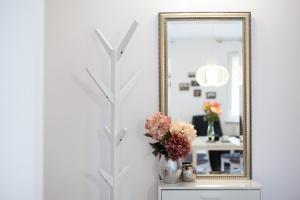 a mirror and a vase with flowers on a dresser at Apartament Parkowy by RENT4YOU in Olsztyn