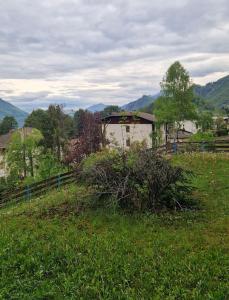 un campo de hierba con una valla y una casa en Valsassina Paradise Apartment - free ski bus just below the building, en Cassina Valsassina