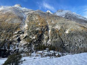 a snow covered mountain with a house in front of it at Baita Chalet La Masun in Chiesa in Valmalenco