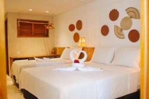 a hotel room with two beds with a towel on the bed at Pousada Vila de Pedra in Jericoacoara