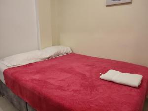 een rood bed met twee witte handdoeken erop bij GURUS FR | Apartamento cerca al Aeropuerto y Terminal 2 Hab in Pereira