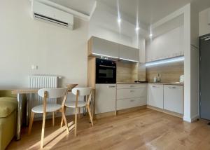 a kitchen with white cabinets and a table and chairs at Opera Park 23 by RENT4YOU in Olsztyn