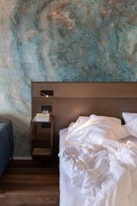 a bed in a bedroom with a painting on the wall at Hotel Baia Azzurra - Lake Front in Nago-Torbole