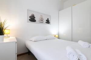 um quarto branco com uma cama branca e algumas toalhas em PrimoPiano - Scalvini em Milão