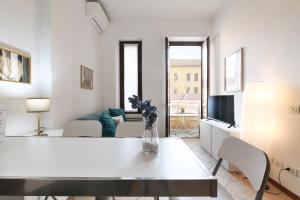 uma sala de estar branca com um vaso de flores sobre uma mesa em PrimoPiano - Scalvini em Milão