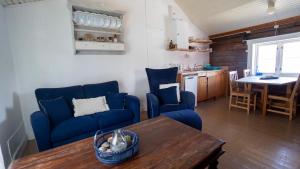 a living room with blue couches and a table at Real fisherman's cabins in Ballstad, Lofoten - nr. 11, Johnbua in Ballstad