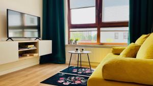 a living room with a yellow couch and a table at Opera Park 128 by RENT4YOU in Olsztyn