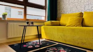 een gele bank in een woonkamer met een tafel bij Opera Park 128 by RENT4YOU in Olsztyn