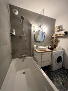 a bathroom with a tub and a washing machine at Joli appartement à Fegersheim in Fegersheim